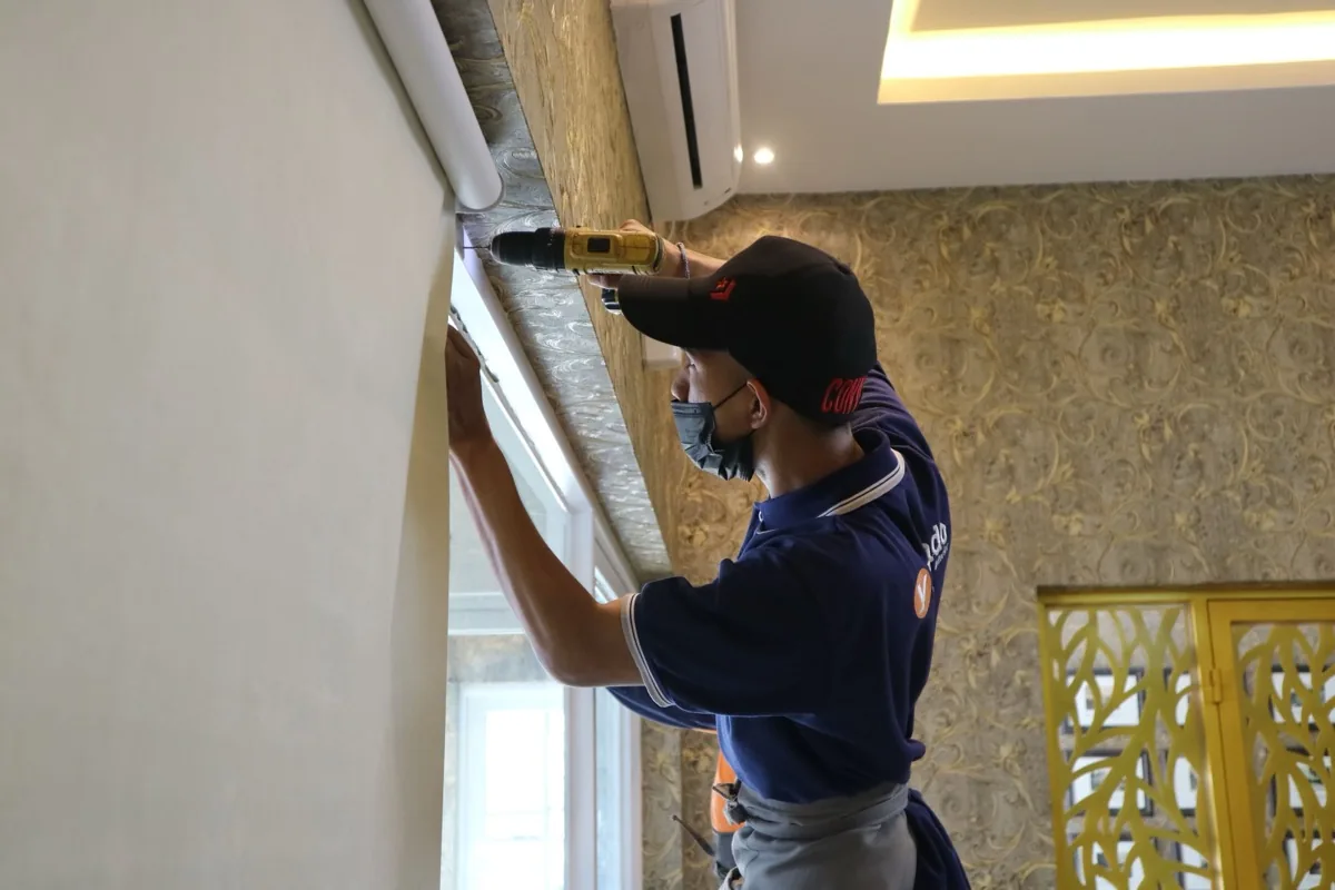 A handyman fitting a blind with a cordless drill